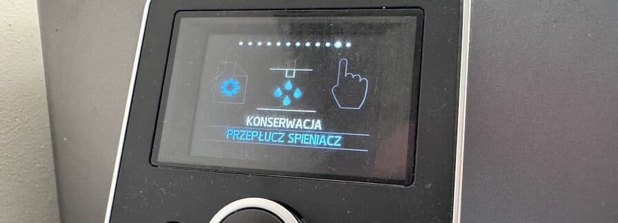 Wyświetlacz ekspresu automatycznego z komunikatem „Konserwacja – przepłucz spieniacz”